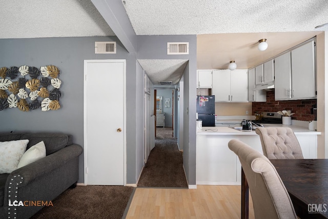 2105 Pinion Springs Cir Unit D, Bakersfield, CA 93309 - kitchen with freestanding refrigerator, stainless steel gas range, under cabinet range hood, beamed ceiling, and light wood-style flooring