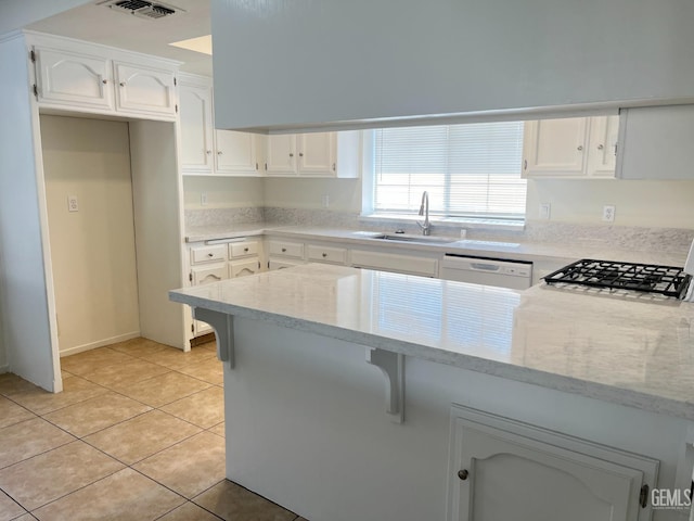 kitchen with white dishwasher, light stone countertops, a sink, white cabinets, and a peninsula