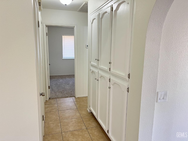 hallway featuring visible vents and light tile patterned floors