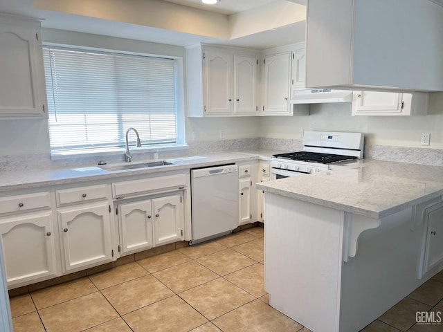 kitchen with a sink, a peninsula, white cabinets, and white appliances