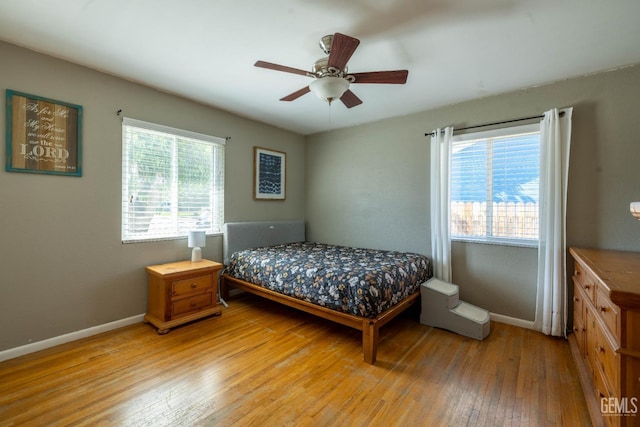 bedroom featuring baseboards, multiple windows, and light wood-type flooring
