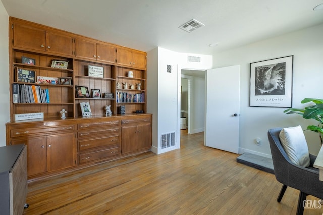 office with baseboards, visible vents, and light wood-style flooring