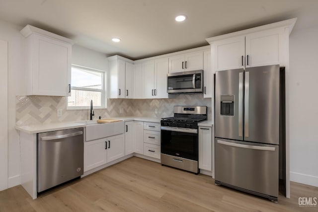 kitchen featuring light countertops, stainless steel appliances, white cabinetry, and a sink