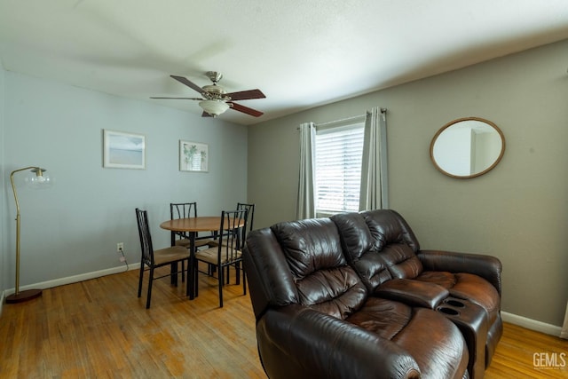 living area with light wood-type flooring, a ceiling fan, and baseboards