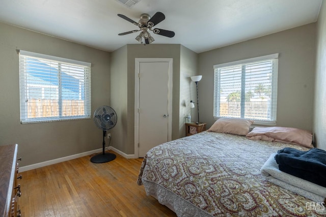bedroom with wood-type flooring, a ceiling fan, and baseboards