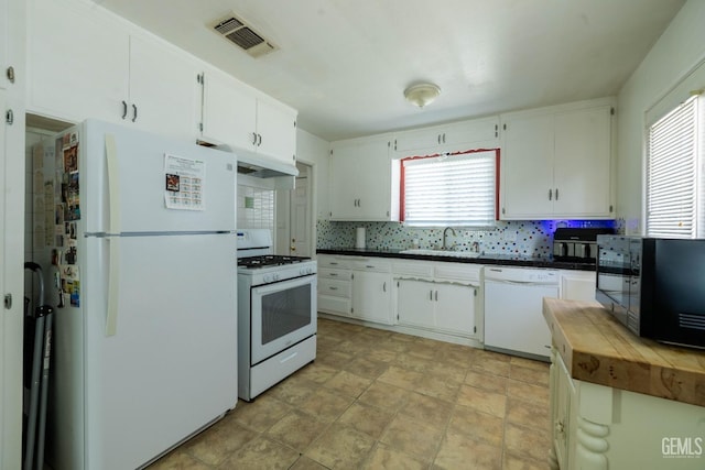 kitchen with visible vents, dark countertops, white appliances, white cabinetry, and a sink