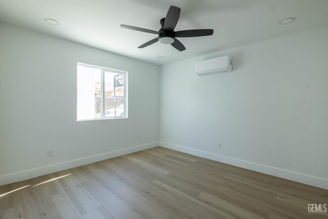 spare room with baseboards, a wall mounted AC, a ceiling fan, and wood finished floors
