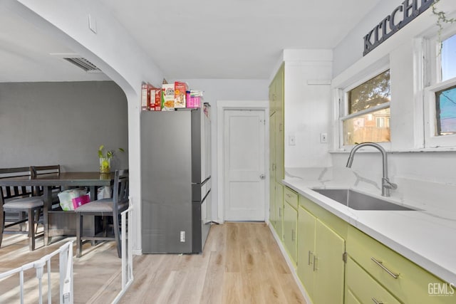 339 Ray St, Bakersfield, CA 93308 - kitchen with freestanding refrigerator, green cabinets, light wood-style flooring, arched walkways, and light stone counters
