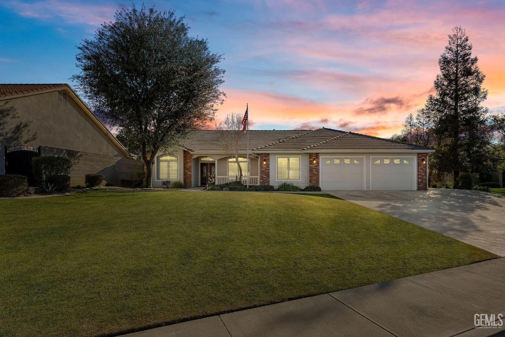 ranch-style house featuring a garage and a lawn