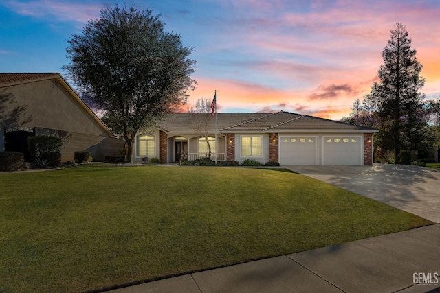 ranch-style house featuring a garage and a lawn