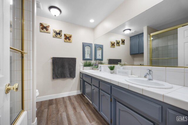 3404 Medallion Rose Ave, Bakersfield, CA 93313 - full bathroom featuring double vanity, wood finished floors, toilet, baseboards, and shower / bath combination with glass door
