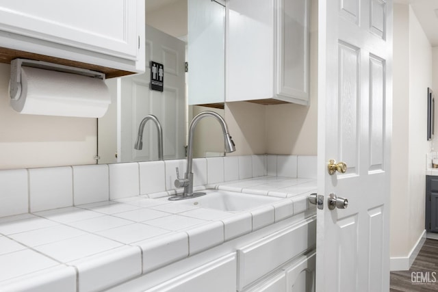 3404 Medallion Rose Ave, Bakersfield, CA 93313 - kitchen view of white cabinets, a sink, baseboards, and tile countertops