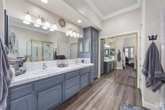 3404 Medallion Rose Ave, Bakersfield, CA 93313 - ensuite bathroom featuring crown molding, double vanity, a shower stall, and wood finished floors