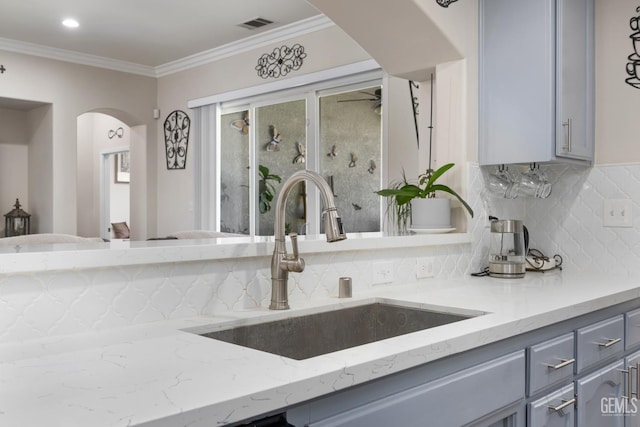 3404 Medallion Rose Ave, Bakersfield, CA 93313 - kitchen with gray cabinets, a sink, backsplash, arched walkways, and crown molding