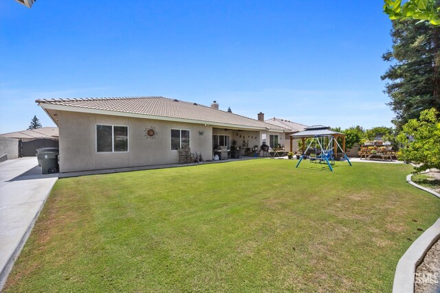 3404 Medallion Rose Ave, Bakersfield, CA 93313 - back of house with stucco siding, a lawn, a gazebo, a chimney, and a playground
