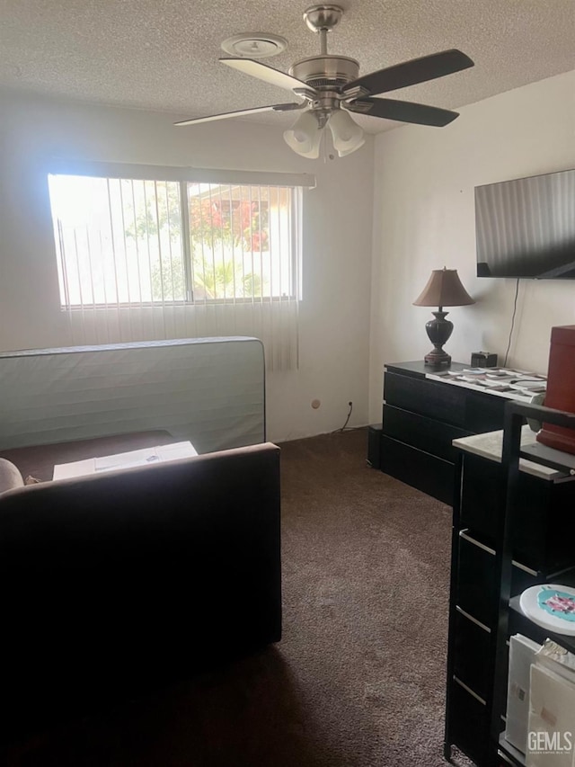 carpeted bedroom featuring ceiling fan and a textured ceiling