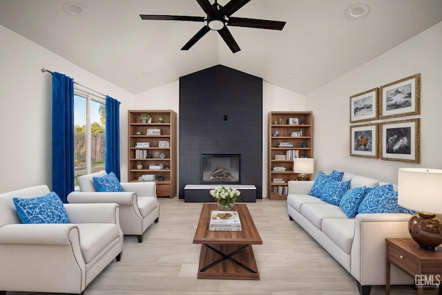 living room with ceiling fan, a large fireplace, and vaulted ceiling