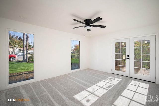 carpeted spare room featuring ceiling fan, a healthy amount of sunlight, and french doors