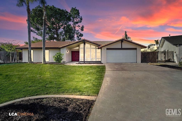 ranch-style house featuring a garage and a yard