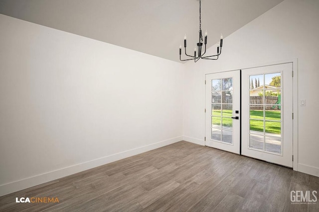 unfurnished dining area featuring a notable chandelier, french doors, lofted ceiling, and hardwood / wood-style flooring