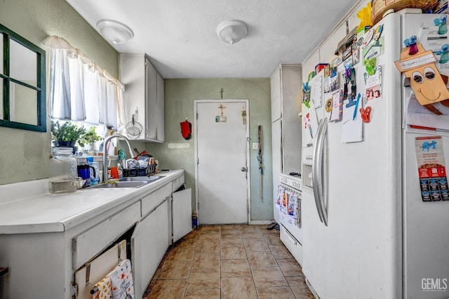 kitchen featuring sink, light tile patterned flooring, a textured ceiling, white appliances, and white cabinets