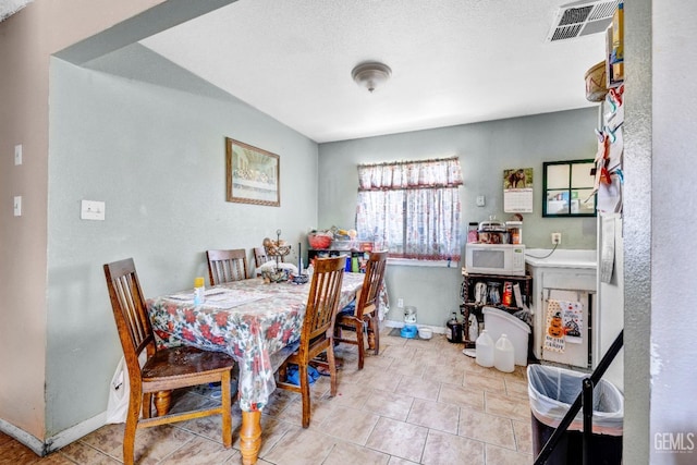 tiled dining area with a textured ceiling