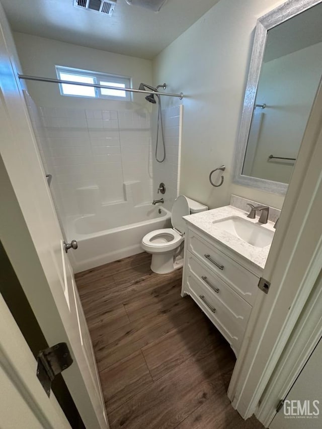 full bathroom with hardwood / wood-style floors, vanity, toilet, and shower / washtub combination