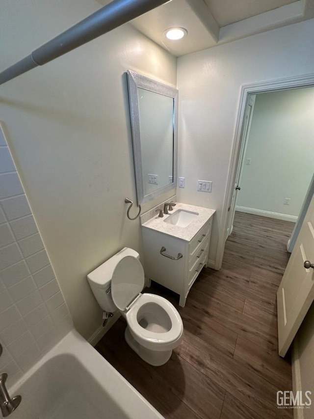 bathroom with a bath, vanity, wood-type flooring, and toilet