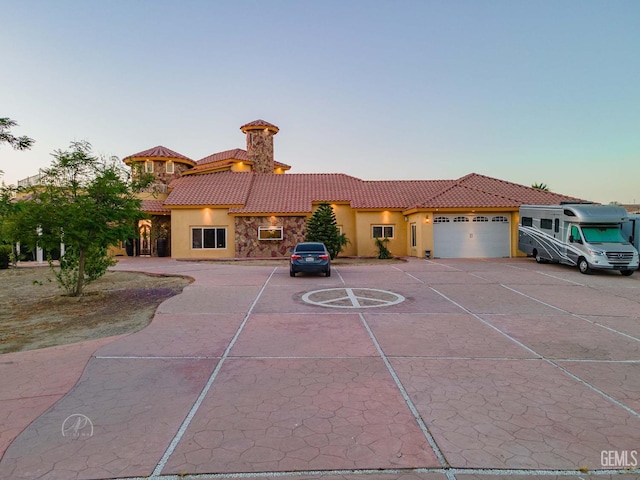 9446 E Kern River Ave, Bakersfield, CA 93308 - mediterranean / spanish home featuring a tiled roof, stucco siding, an attached garage, and asphalt driveway