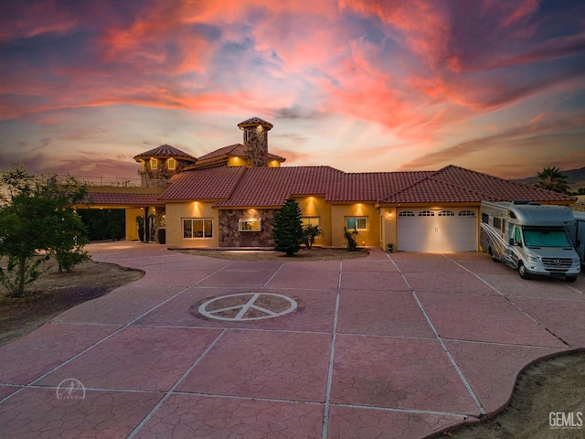 9446 E Kern River Ave, Bakersfield, CA 93308 - mediterranean / spanish house featuring a tile roof, stucco siding, curved driveway, a garage, and a chimney