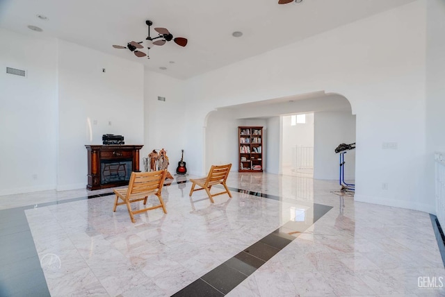 9446 E Kern River Ave, Bakersfield, CA 93308 - sitting room featuring arched walkways, ceiling fan, marble tiled flooring, and a high ceiling