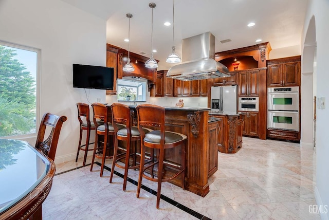 9446 E Kern River Ave, Bakersfield, CA 93308 - kitchen featuring island range hood, stainless steel appliances, a peninsula, a kitchen breakfast bar, and healthy amount of natural light