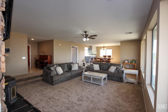 living room featuring carpet, a wood stove, and ceiling fan