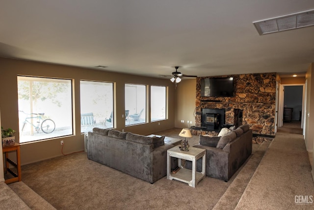 living room featuring ceiling fan, a wood stove, and carpet floors