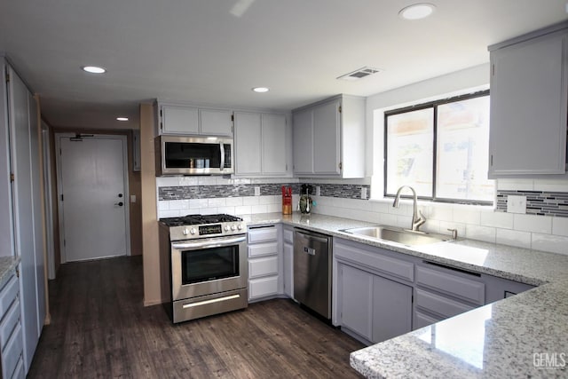 kitchen featuring gray cabinetry, sink, dark wood-type flooring, light stone counters, and appliances with stainless steel finishes