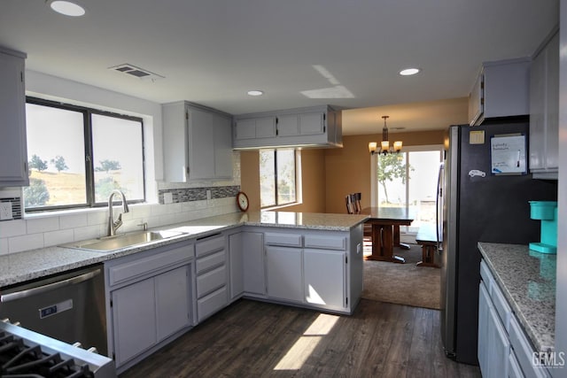 kitchen featuring sink, decorative light fixtures, a notable chandelier, dark hardwood / wood-style flooring, and kitchen peninsula