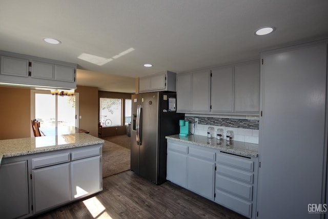 kitchen featuring backsplash, stainless steel fridge, dark hardwood / wood-style flooring, and light stone countertops