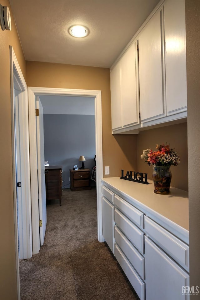 hall with dark carpet and a textured ceiling