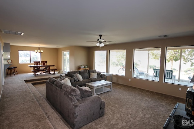 living room featuring dark carpet and ceiling fan with notable chandelier