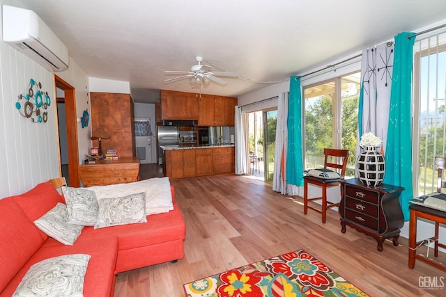 living room with ceiling fan, a wall unit AC, and light hardwood / wood-style flooring