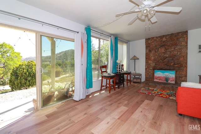 interior space with a stone fireplace and ceiling fan