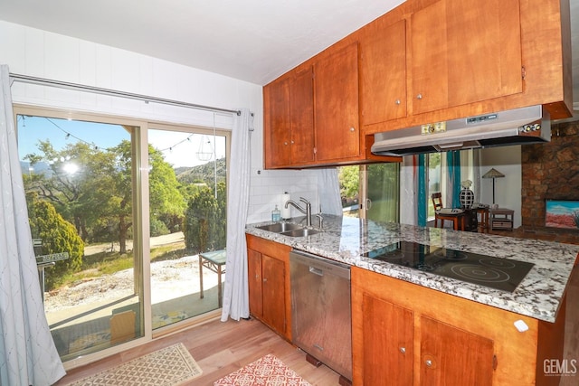 kitchen with light stone countertops, sink, stainless steel dishwasher, black electric stovetop, and light wood-type flooring