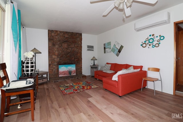 living room featuring hardwood / wood-style floors, ceiling fan, an AC wall unit, and a fireplace