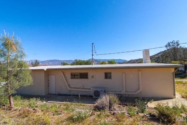 back of property with a mountain view and ac unit