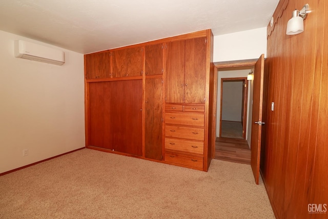 unfurnished bedroom featuring light colored carpet, an AC wall unit, and a closet