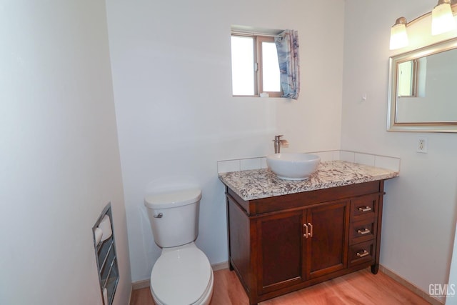 bathroom with wood-type flooring, vanity, and toilet