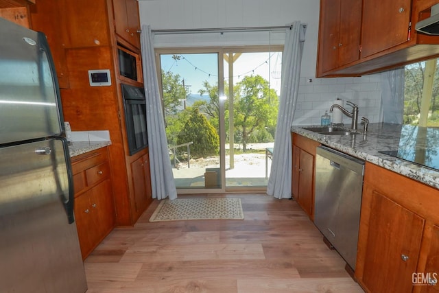 kitchen featuring exhaust hood, sink, light stone counters, and black appliances