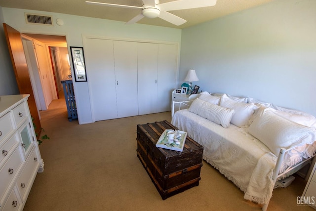 bedroom featuring a closet, visible vents, light colored carpet, and a ceiling fan