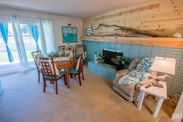 carpeted dining area featuring a textured ceiling, a fireplace with raised hearth, and wood walls