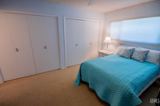 carpeted bedroom with a textured ceiling and two closets